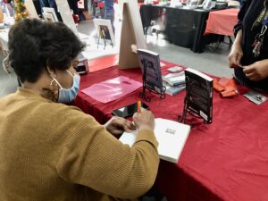 Above: The Detroit Book City Holiday Book Festival was held in December of 2021. Book signings give authors the opportunity to network with other authors. Deborah Walker, whose pen name is Nova Wallace, is shown here autographing her book, “Bipolar Bears.” She sold out of her books during the festival.